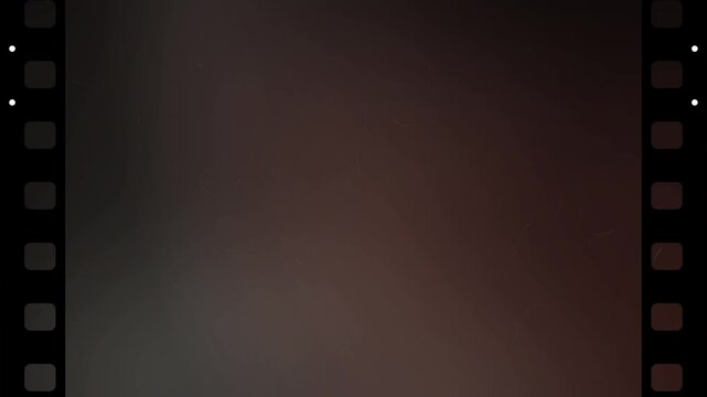 Old vintage film strip background with dark reddish brown tones featuring cinematic artifacts like scratches dust and grain for retro movie overlays and analog video effects
