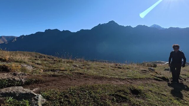 4k video of a hiker walking on a mountain path with scenic backlight and peaks in Georgia.