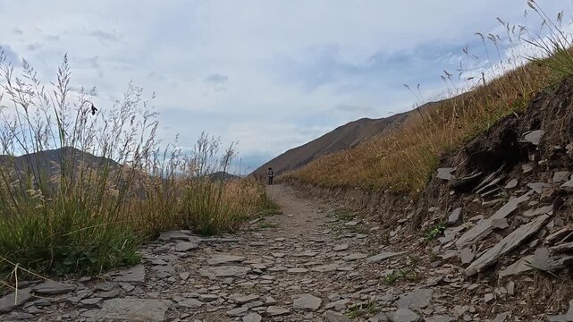4k video of a hiker walking forward on a rocky mountain path in Juta valley, Georgia.