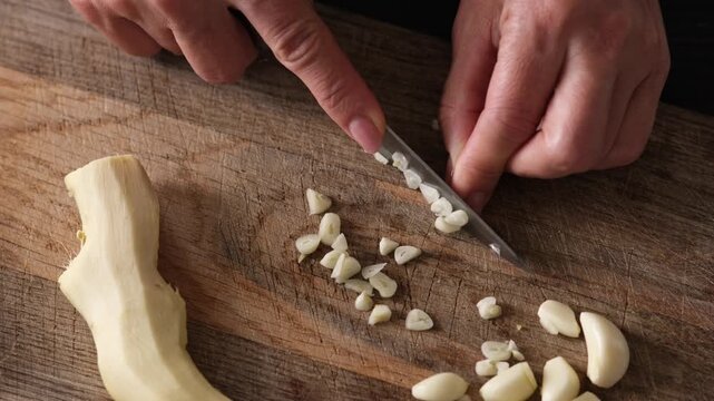 Close-Up Top View Of Woman Slicing Garlic