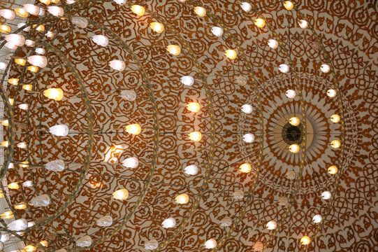 Ornate mosque ceiling with symmetrical Islamic lights and golden detail