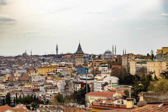 High angle panoramic cityscape of Istanbul with Galata Tower, Beyazit Tower and Suleymaniye mosque. Historic district architecture, old town rooftops under overcast sky, spring day, Turkey.