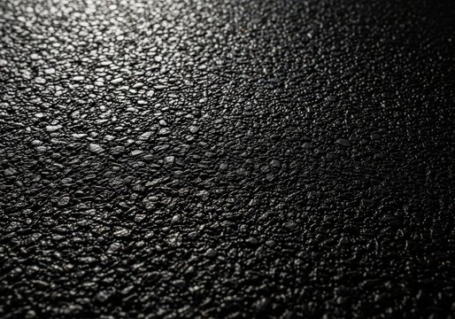 Close up view of a rough, dark black asphalt texture background showing granular material, suitable for abstract design or construction themes, industrial, bitumen, copy space