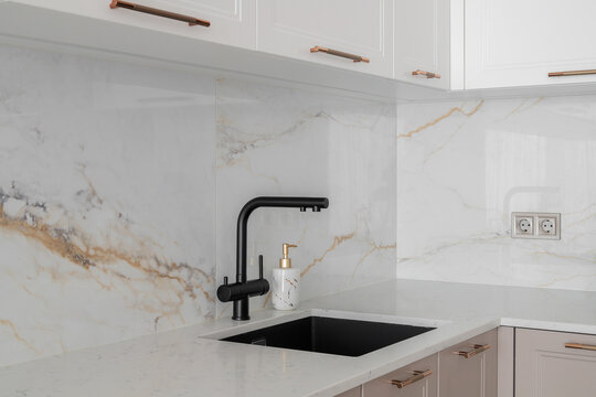 Black kitchen faucet and marble backsplash