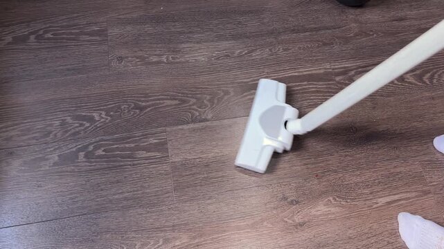Vacuum cleaner head moving on wood floor cleaning dust