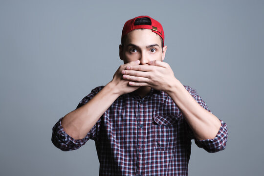Young man covering mouth feeling surprised and speechless