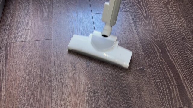 Vacuum cleaner head moving on wood floor cleaning dust