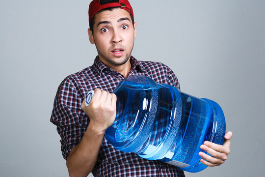 Man looking surprised holding heavy water cooler bottle