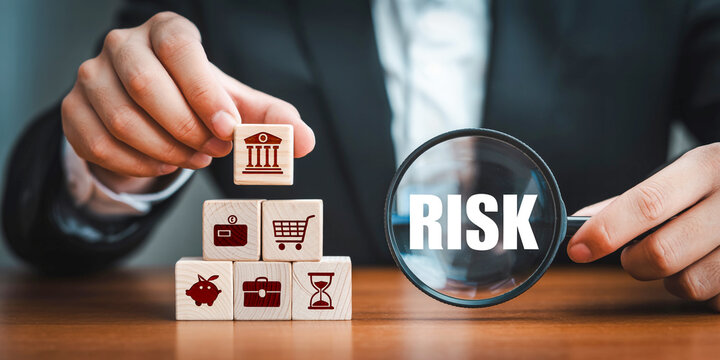 Businessman assessing risk with financial icons on wooden blocks