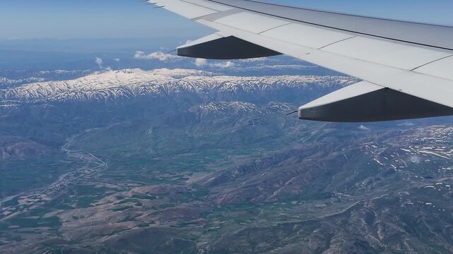 Stunning aerial view of snowy Munzur Mountains from an airplane window. Majestic snow capped peaks and beautiful valleys of Turkey during a scenic flight. Majestic mountain landscape background.
