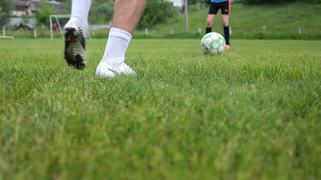 Male feet of professional footballers passing soccer ball on stadium at summer day. Legs of sportsmen kicking ball at green field. Young men training at meadow. Concept of a freestyle football