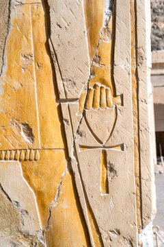 Ankh, an ancient Egyptian symbol known as the Key of Life, in a hand of a Pharaoh god on the wall of the temple of Queen Hatshepsut near Luxor, Egypt