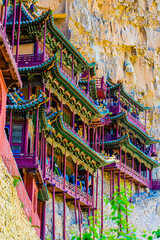 Obraz premium Shanxi, China - May 10 2026: The dramatic façade of Xuankong Temple clings to a sheer cliff, showcasing extraordinary ancient engineering and harmonious integration with the natural landscape