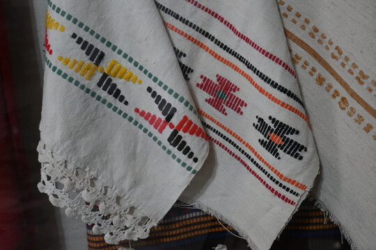 Close-up of rich colorful folk embroidery detail on white linen fabric.