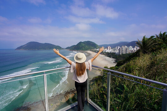 Young tourist woman on viewpoint with raised arms in Guaruja, Sao Paulo State, Brazil