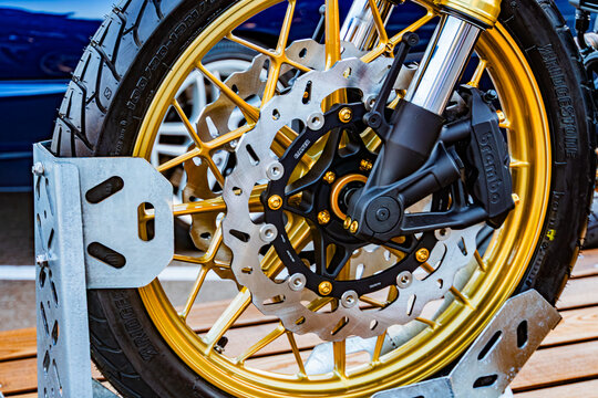 Close-up view of disassembled dirt bike front wheel with knobby tire and gold anodized rims, displayed on a wooden surface Detailed metal parts such as spokes, hubs  Kyiv, Ukraine September 21, 2025