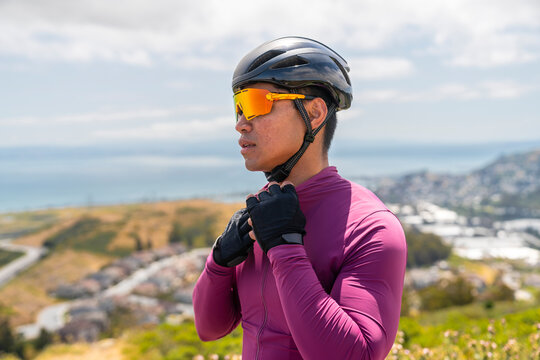 Cyclist taking break standing outside atop hill with view bay area 

