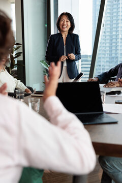 Businesswoman leading team meeting with laughter in modern office