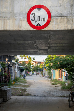 Vehicle height limit road sign under concrete bridge over narrow village street