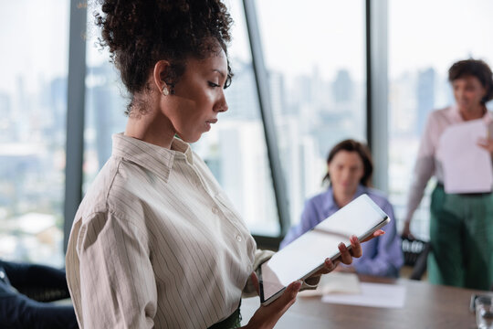 Businesswoman with digital tablet at meeting in modern office.