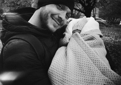 Man with baby in blanket outdoors