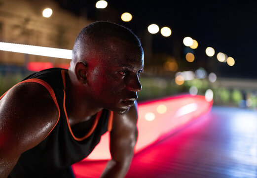 Sweaty black male athlete resting at night