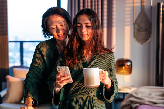 Mother and daughter sharing a mobile phone during morning coffee