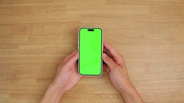 Hands Using Smartphone with Chroma Key Green Screen on Wooden Table