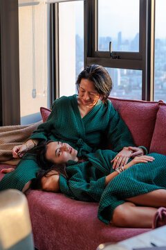 Mother comforting daughter resting on her lap at home