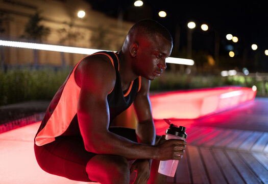 Exhausted African American athlete drinking water