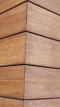 Vertical video. Close-up of wood-look facade tiles on modern house exterior with clean corner detail.