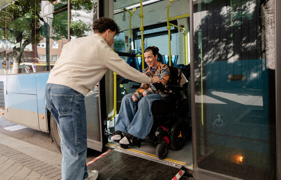 Man assisting woman in wheelchair boarding bus