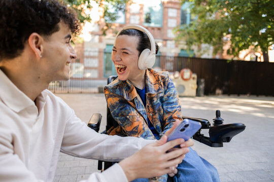 Young friends enjoying shared content on smartphone, laughing