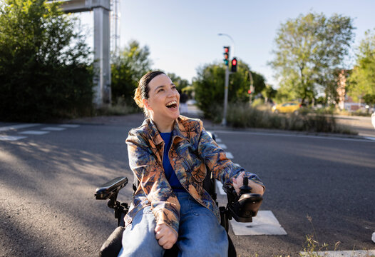 Happy woman with disability driving electric wheelchair