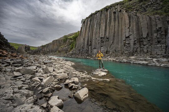 Tourist standing by the river in Stu&eth;lagil Canyon, turquoise blue river between basalt columns, Egilsstadir, Iceland