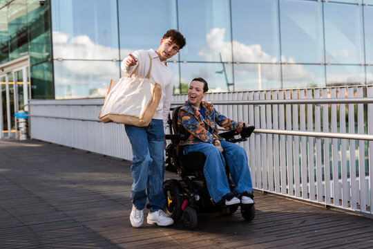 Young man pointing sharing moment with woman in power wheelchair