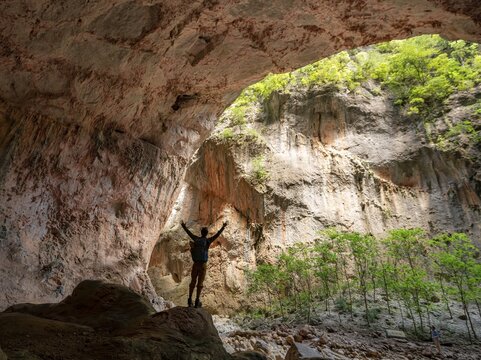 Walker stretching his arms in the air, cave Cueva de La Ermita, canyon, steep cliffs of the Garganta Verde, Sierra de C&aacute;diz, province of C&aacute;diz, Spain