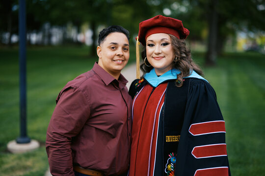 portrait of lgbtq doctorate graduate with her wife on campus