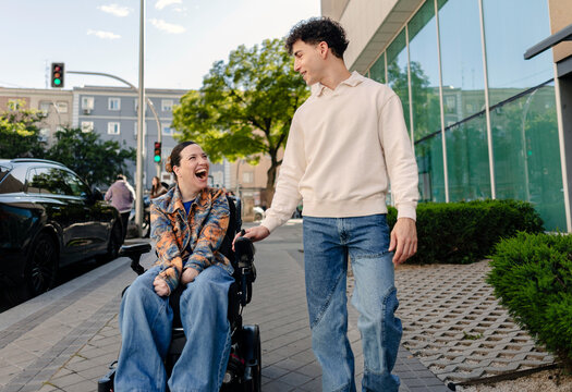 Young woman in wheelchair laughing on city street