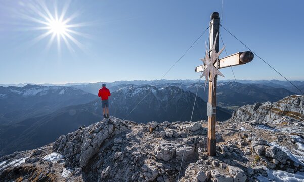 Mountaineer at the summit of the Guffertspitze, summit with summit cross, sun star, in autumn, Brandenberg Alps, Tyrol, Austria
