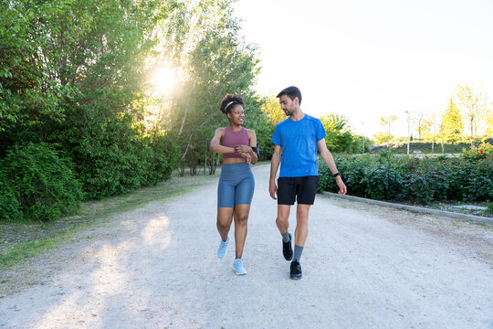 Diverse couple jogging together outdoors monitoring progress