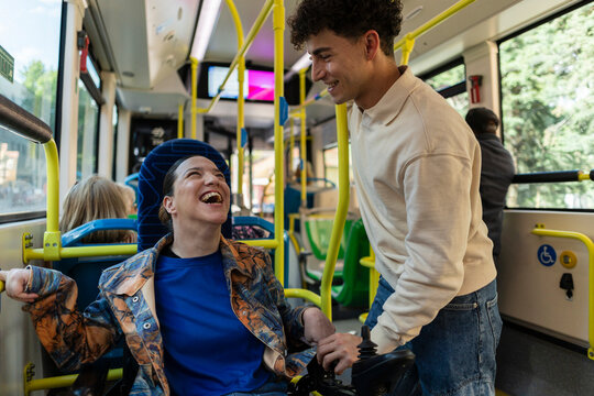 Woman in wheelchair laughing with friend on bus