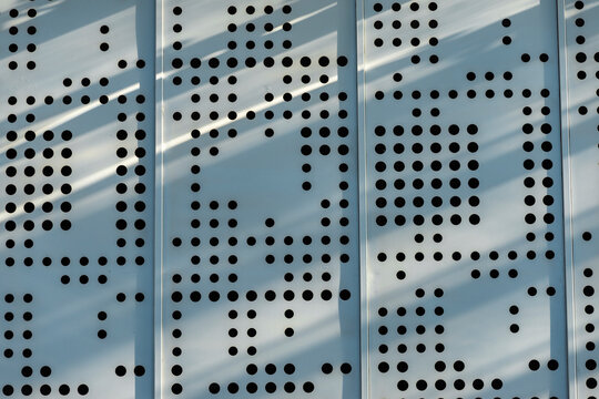 Perforated facade pattern beneath diagonal light bands