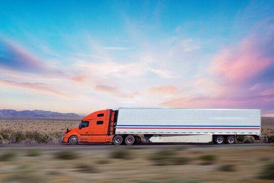 Semi-truck driving on the highway at sunset 
