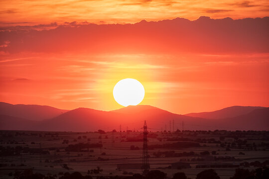 Sunset over fields with mountains and power lines