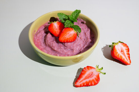 Creamy fruit smoothie bowl garnished with ripe strawberries, wholesome plant-based meal perfect for breakfast.