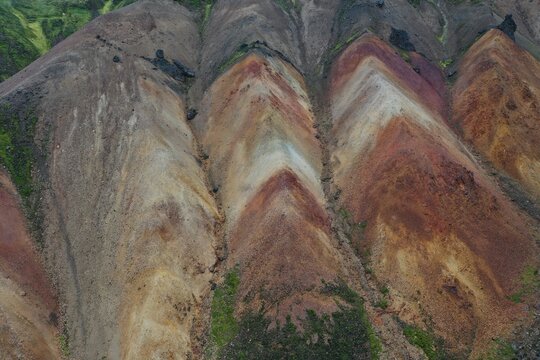 Aerial view of the colorful rhyolite mountains of Kerlingarfjoll with vibrant orange, red, and brown slopes in Hella, Rangarthing ytra, Iceland.