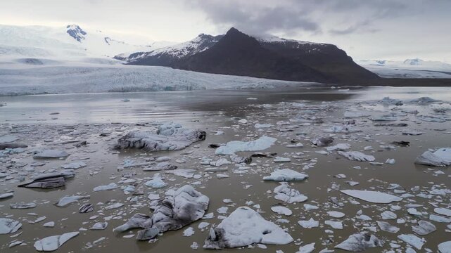 un lac aux eaux troubles couvert de morceaux du glacier  qui est en fond