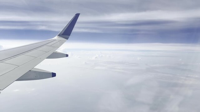 Airplane wing flying above a bright cloud layer under a dramatic blue sky, scenic aerial view from passenger window showing commercial aviation, altitude travel, freedom, journey and serene atmosphere