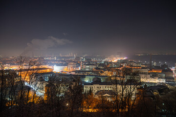Naklejka premium Nighttime view of Kiev, Ukraines Podil district from a high vantage point Densely populated urban landscape with varied building heights and architectural styles Warmly lit streets, traffic lights
